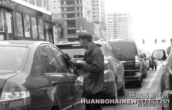 在建設(shè)路新華道路口“擦車”的行乞者。田菲菲攝